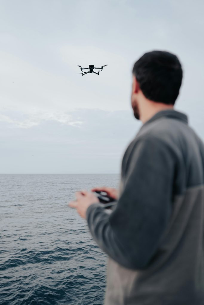 pexels-photo-15842322-15842322 A man controls a flying drone over the ocean, showcasing modern technology and hobbyist interests.