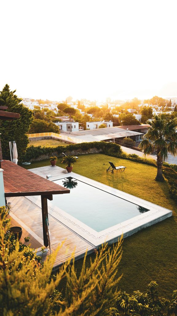 Stunning aerial image of a luxurious backyard with a swimming pool during a warm sunset.